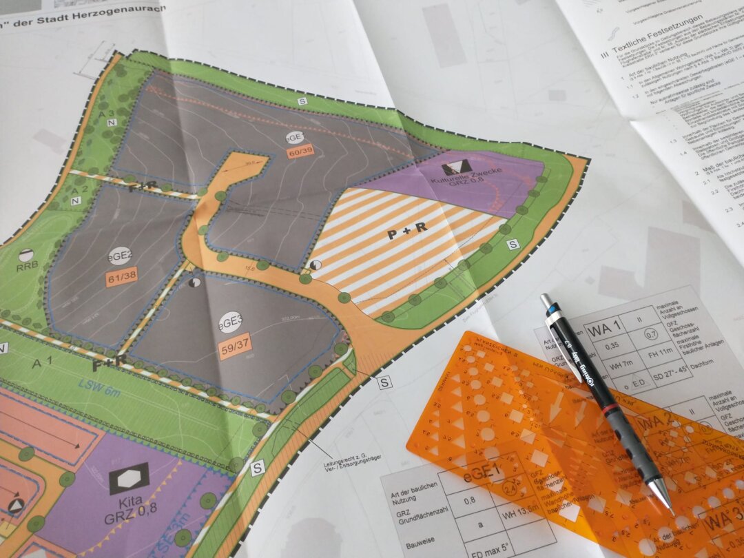 Stift und Zeichenschablone auf einem Umlegungsplan