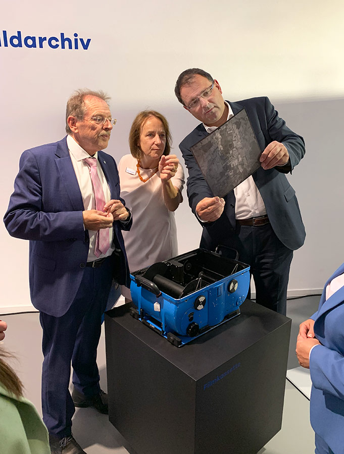 Eröffnung der Sonderausstellung im Bayerischen Landesluftbildzentrum Drei Personen betrachten ein altes Luftbild
