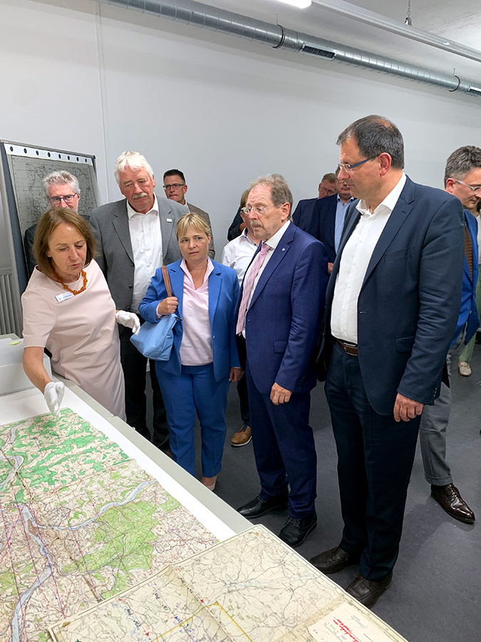 Eröffnung der Sonderausstellung im Bayerischen Landesluftbildzentrum Personen lassen sich etwas auf einer Karte erklären