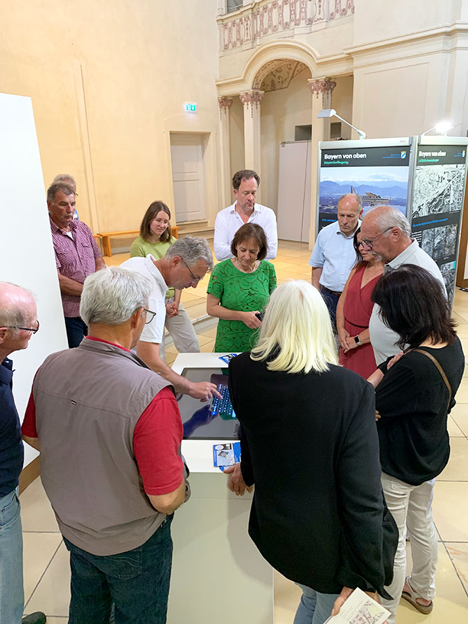 Eröffnung der Wanderausstellung "Bayern von oben" in Eichstätt Personen stehen um einen Touch-Bildschirm herum